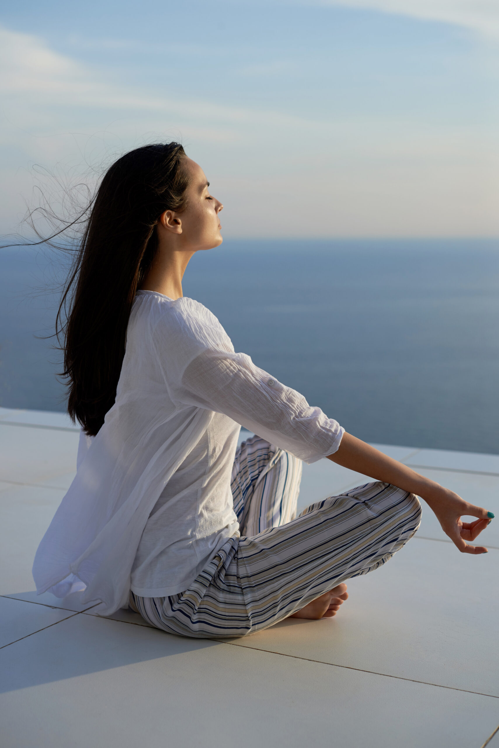 storyblocks young woman practice yoga meditaion on sunset with ocean view in background Bd CPvZO2 scaled